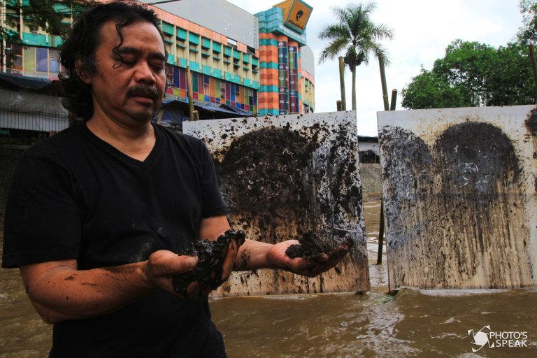 Seniman Tisna Sanjaya menunjukan tanah untuk melukis di Area Sungai Cikapundung, Jalan Ir.Soekarno, Kota Bandung, Jawa Barat, Sabtu (29/10/2016). Lukisan tersebut merupakan kritik kepada pemerintah terhadap begitu mudahnya perijinan pembangunan dikawasan resapan air, tepatnya di Kota Bandung bagian utara dan timur. Pembangunan di daerah tersebut menyebabkan kurangnya resapan air ketika hujan yang mengakibatkan sering terjadinya banjir. Dalam aksinya, masyarakat pun diimbau turut andil dalam pengelolaan sampah yang menjadi tugas bersama mengatasi masalah kerusakan lingkungan. PHOTO'S SPEAK/Adi Maulana Ibrahim