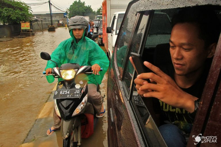 Pengguna kendaraan memanfaatkan gadget untuk memotret suasana banjir di Jalan Soekarno Hatta, Kecamatan Gedebage, Kota Bandung, Rabu, (2/10/2016). Setiap musim hujan, Gedebage memang sudah menjadi langganan banjir. Teknologi anti banjir telah diupayakan Pemkot Bandung 2 bulan lalu yaitu tol air yang dibangun di kawasan tersebut, tidak mampu menahan curah hujan yang tinggi. PHOTO'S SPEAK/ Fajar Q A